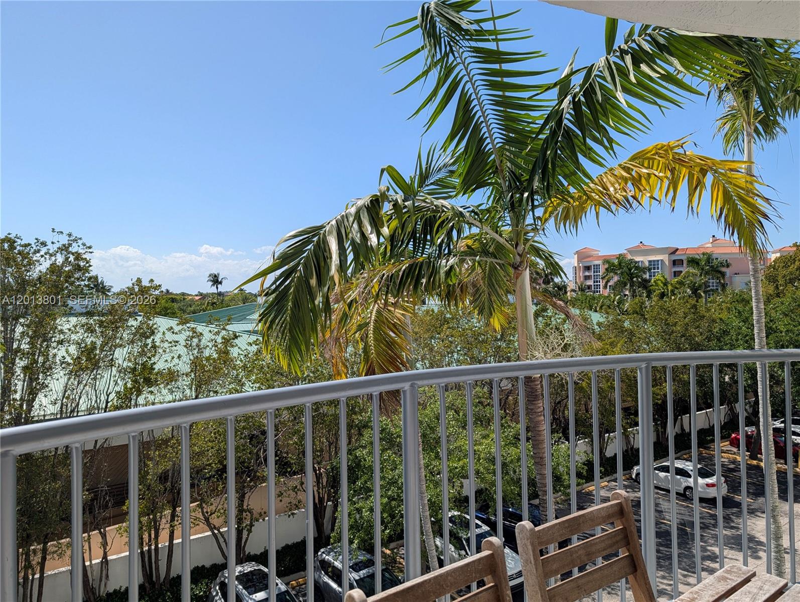 A view from a balcony overlooking a parking lot, trees, and a distant building — 210 Sea View Dr # 405, Key Biscayne FL 33149, KEY BISCAYNE, FL