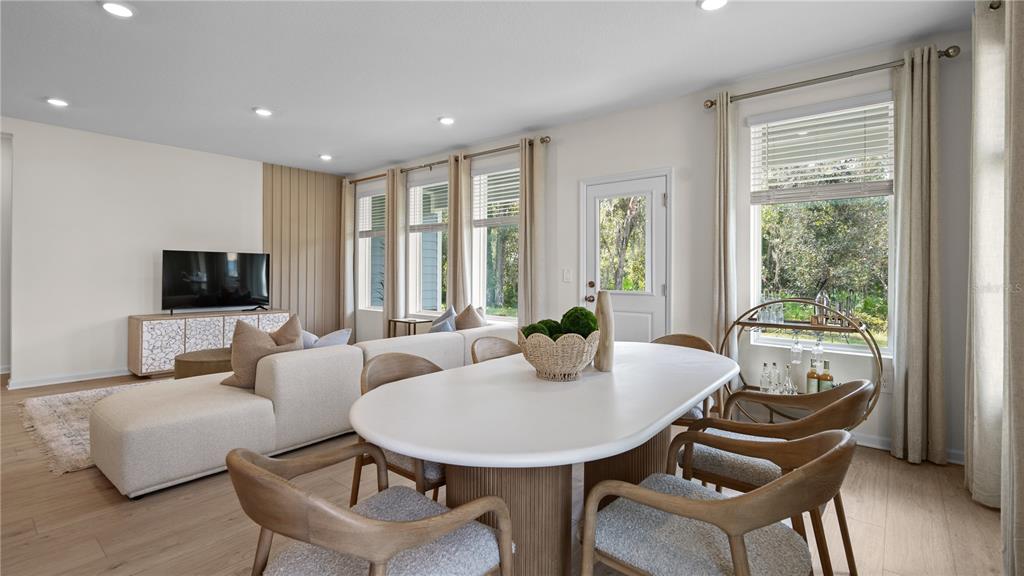 An open-concept living and dining area features light wood flooring, modern furniture, and large windows — 633 RUTH AVENUE, HAINES CITY, FL
