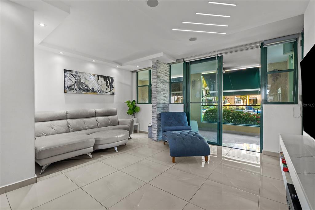A living room features a gray sofa, a blue chaise lounge, and sliding glass doors — Carretera 187 Km 23.6 AQUATIKA UNIT 1501, LOIZA, PR