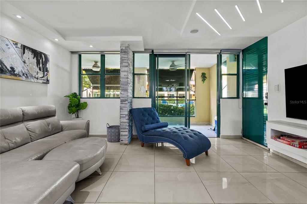 A living room features a grey sectional sofa, a blue chaise lounge, and tile flooring — Carretera 187 Km 23.6 AQUATIKA UNIT 1501, LOIZA, PR