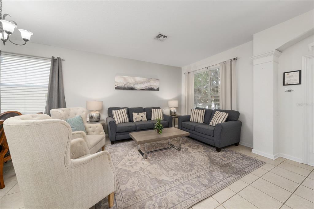 A living room features two dark sofas, an armchair, and a coffee table on tile — 7765 TOSTETH STREET, KISSIMMEE, FL