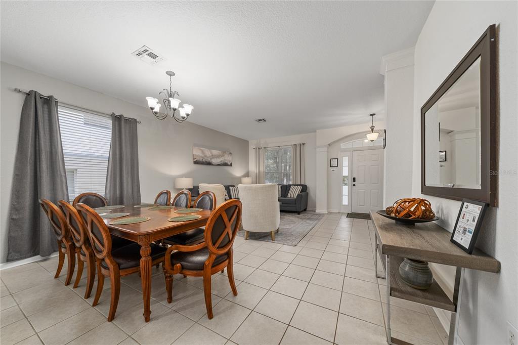 A dining area with a wooden table and chairs sits adjacent to a living room — 7765 TOSTETH STREET, KISSIMMEE, FL