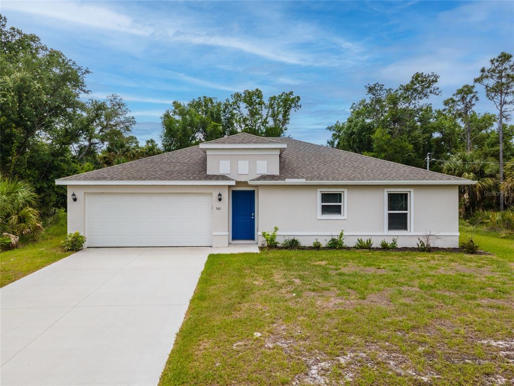 A single-story house with a white garage, blue front door, and a concrete driveway — 1326 GLENAN ROAD, NORTH PORT, FL