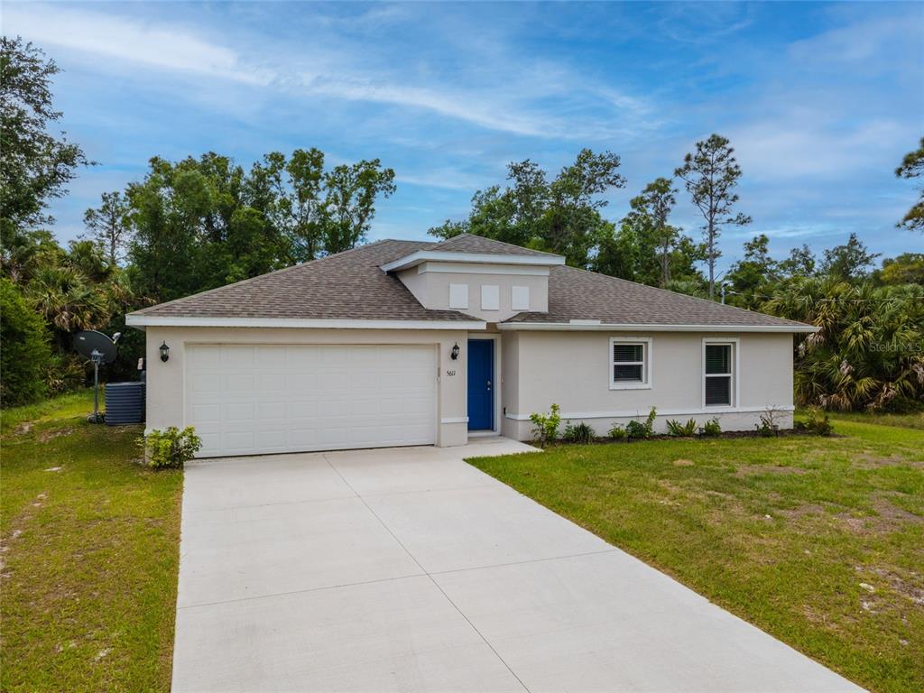 A single-story house with a white stucco exterior, a blue front door, and a concrete driveway — 1326 GLENAN ROAD, NORTH PORT, FL