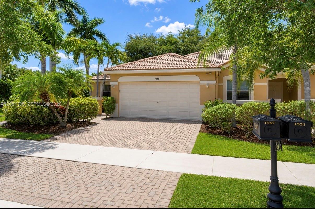 A single-story house with a beige stucco exterior, a tiled roof, and a paved driveway — 1547 Zenith Way, Weston FL 33327, WESTON, FL