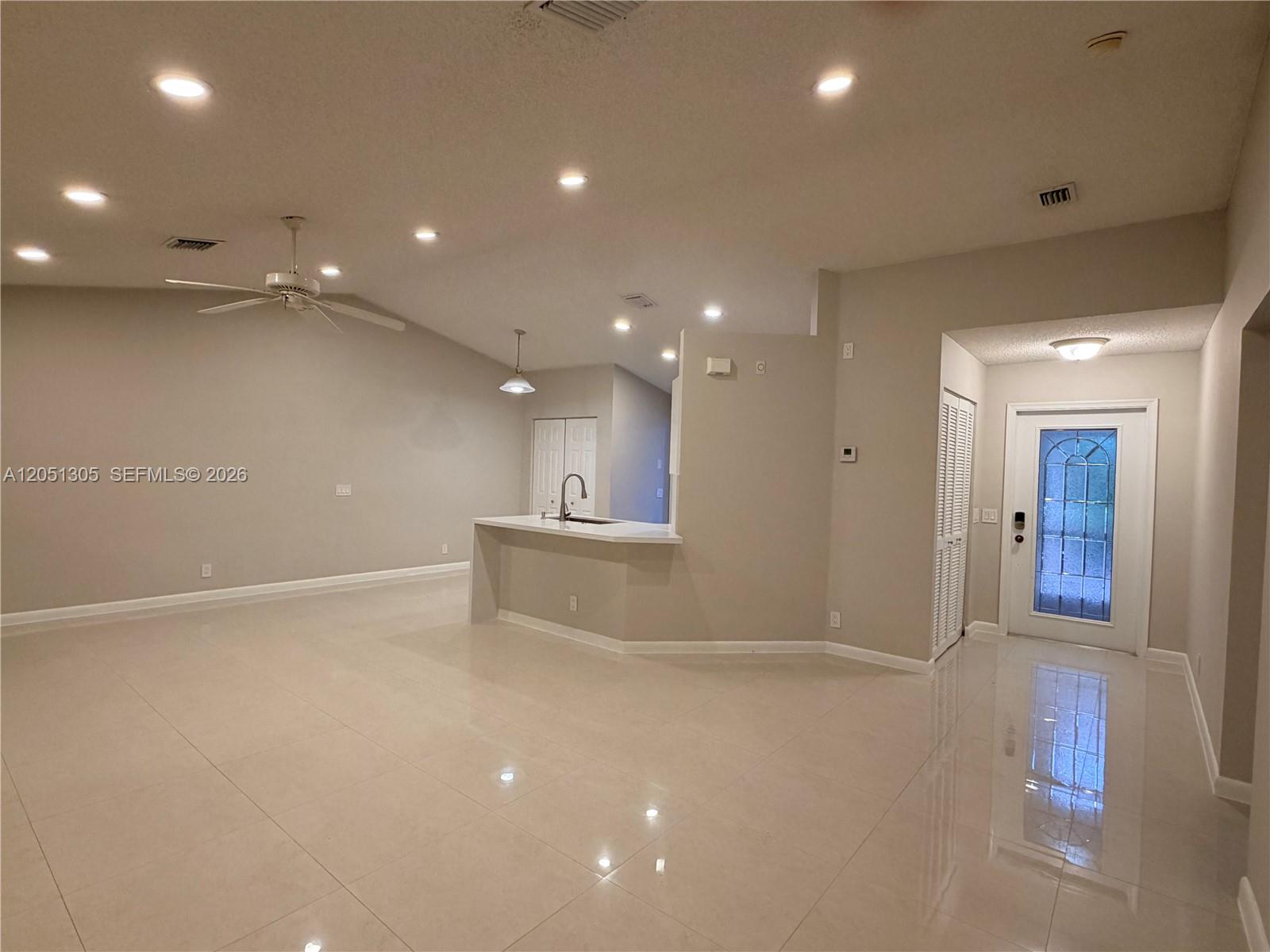 An open-concept living area features light tile flooring, recessed lighting, and a kitchen peninsula — 1547 Zenith Way, Weston FL 33327, WESTON, FL