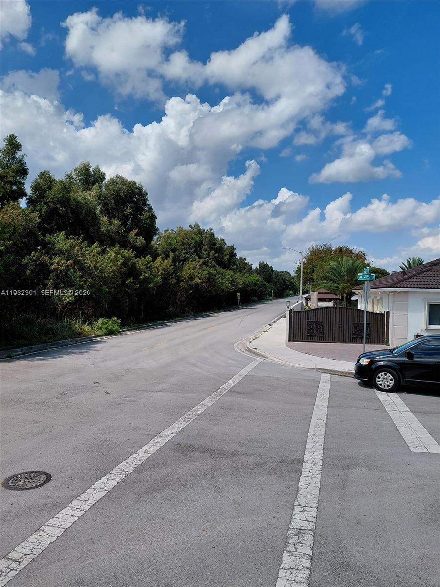 A paved street intersection features a black car parked near a gated residential property — 168xx 45th st, Miami FL 33185, MIAMI, FL