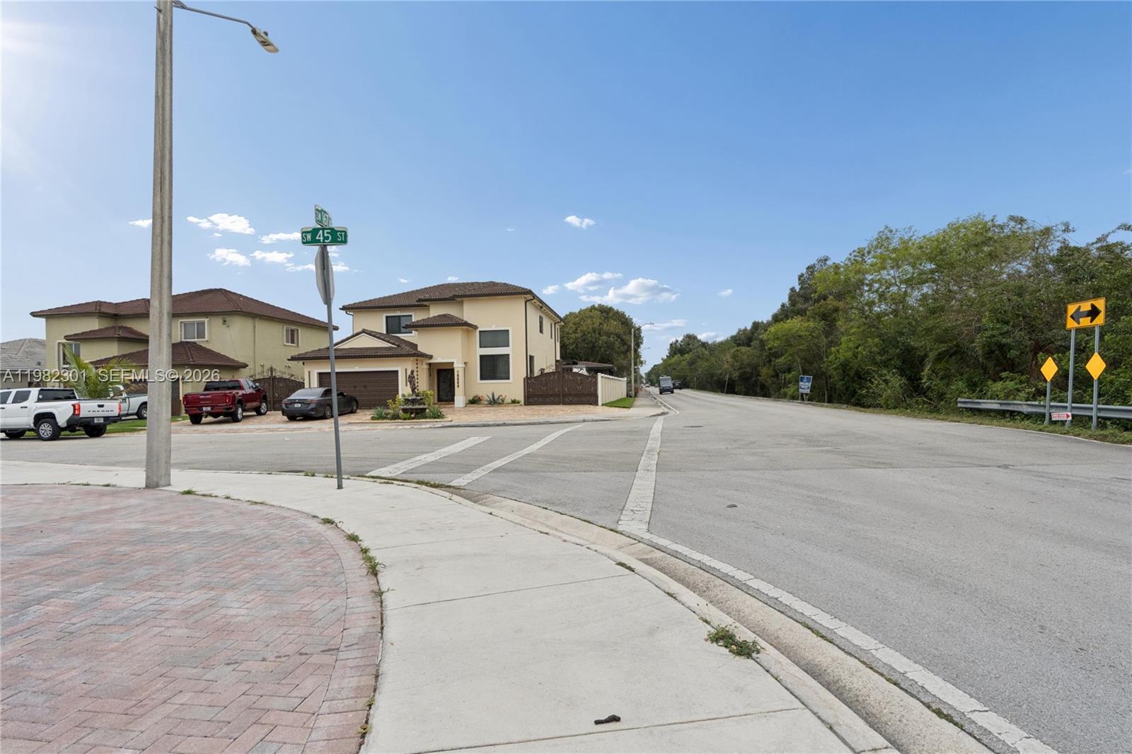 An exterior view of a suburban street corner featuring a two-story house and road signs — 168xx 45th st, Miami FL 33185, MIAMI, FL
