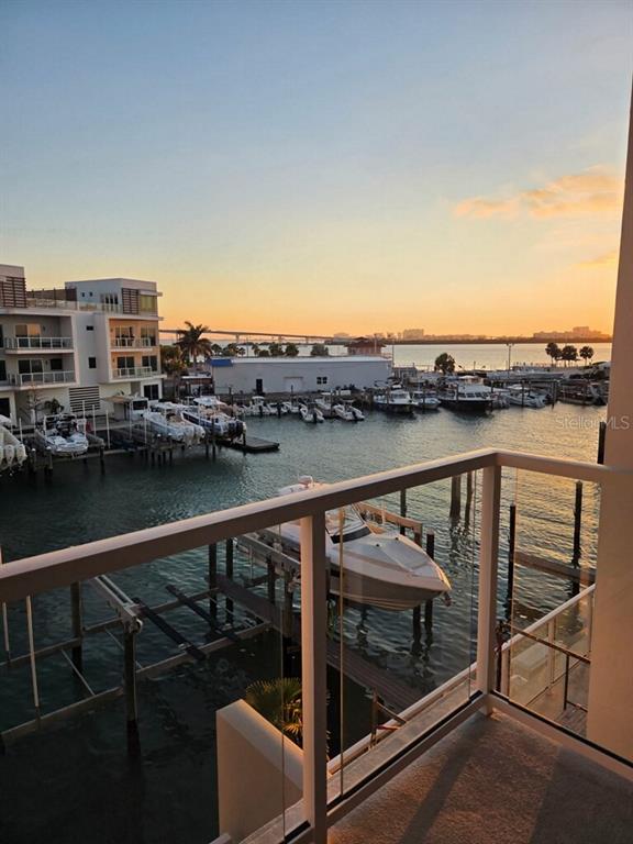 A balcony view overlooks a marina with docked boats and a bridge at sunset — 920 N OSCEOLA AVENUE UNIT 307, CLEARWATER, FL