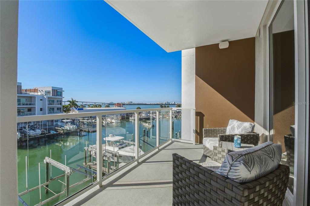 A balcony with outdoor furniture overlooks a marina and a distant bridge under clear skies — 920 N OSCEOLA AVENUE UNIT 307, CLEARWATER, FL