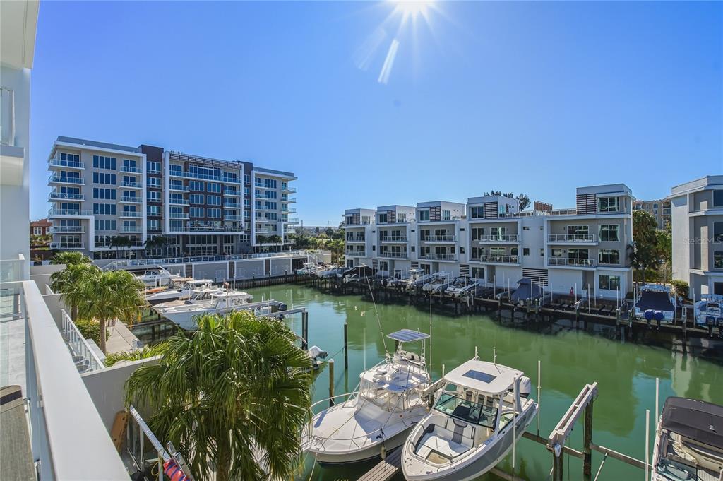 A view from a balcony overlooking a marina with docked boats and modern residential buildings — 920 N OSCEOLA AVENUE UNIT 307, CLEARWATER, FL