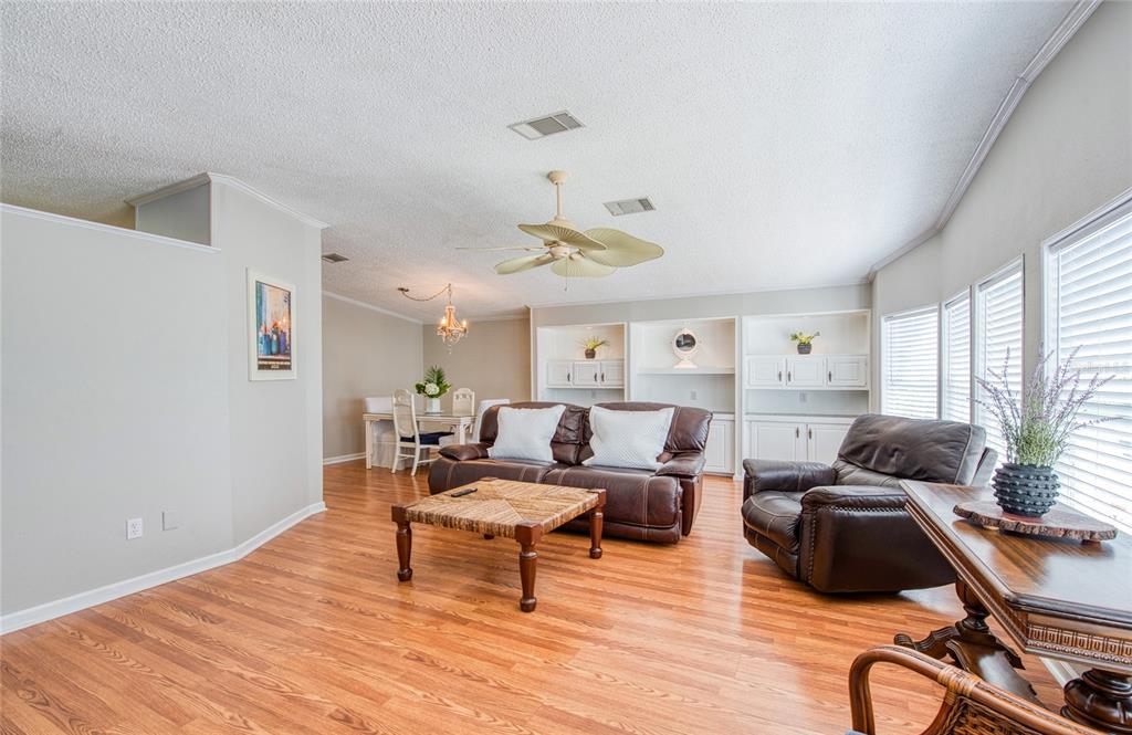 A living room features wood flooring, a ceiling fan, built-in shelving, and leather furniture — 480 TROUT LANE, OLDSMAR, FL