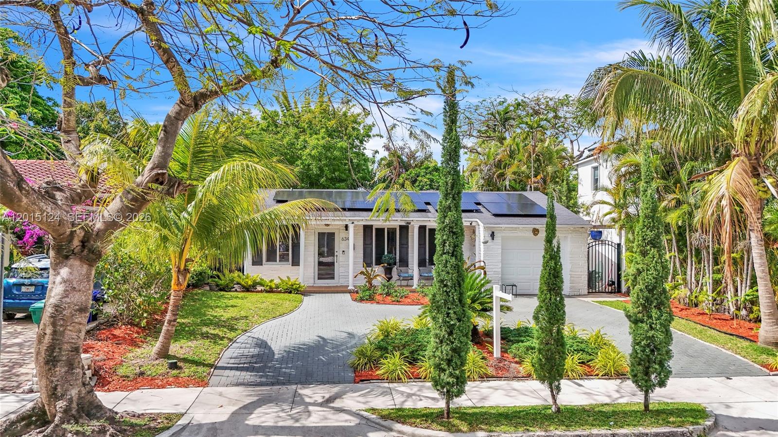 A single-story white brick house features solar panels on the roof and a paved driveway — 634 NE 72nd Ter, Miami FL 33138, MIAMI, FL