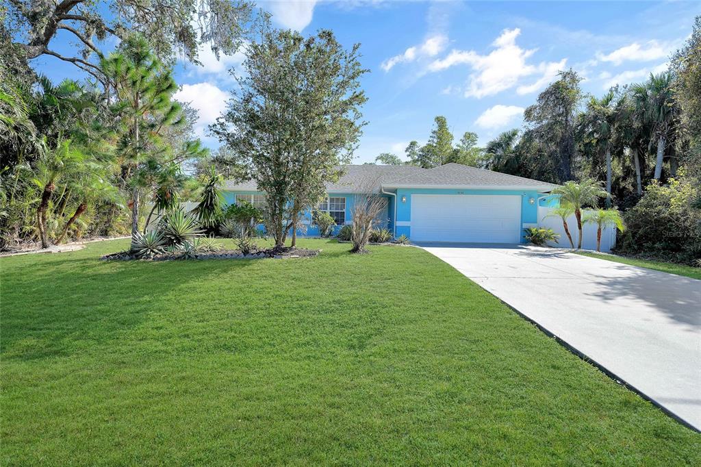 A single-story house with bright blue siding and a white garage sits behind a lawn — 4040 S CRANBERRY BOULEVARD, NORTH PORT, FL