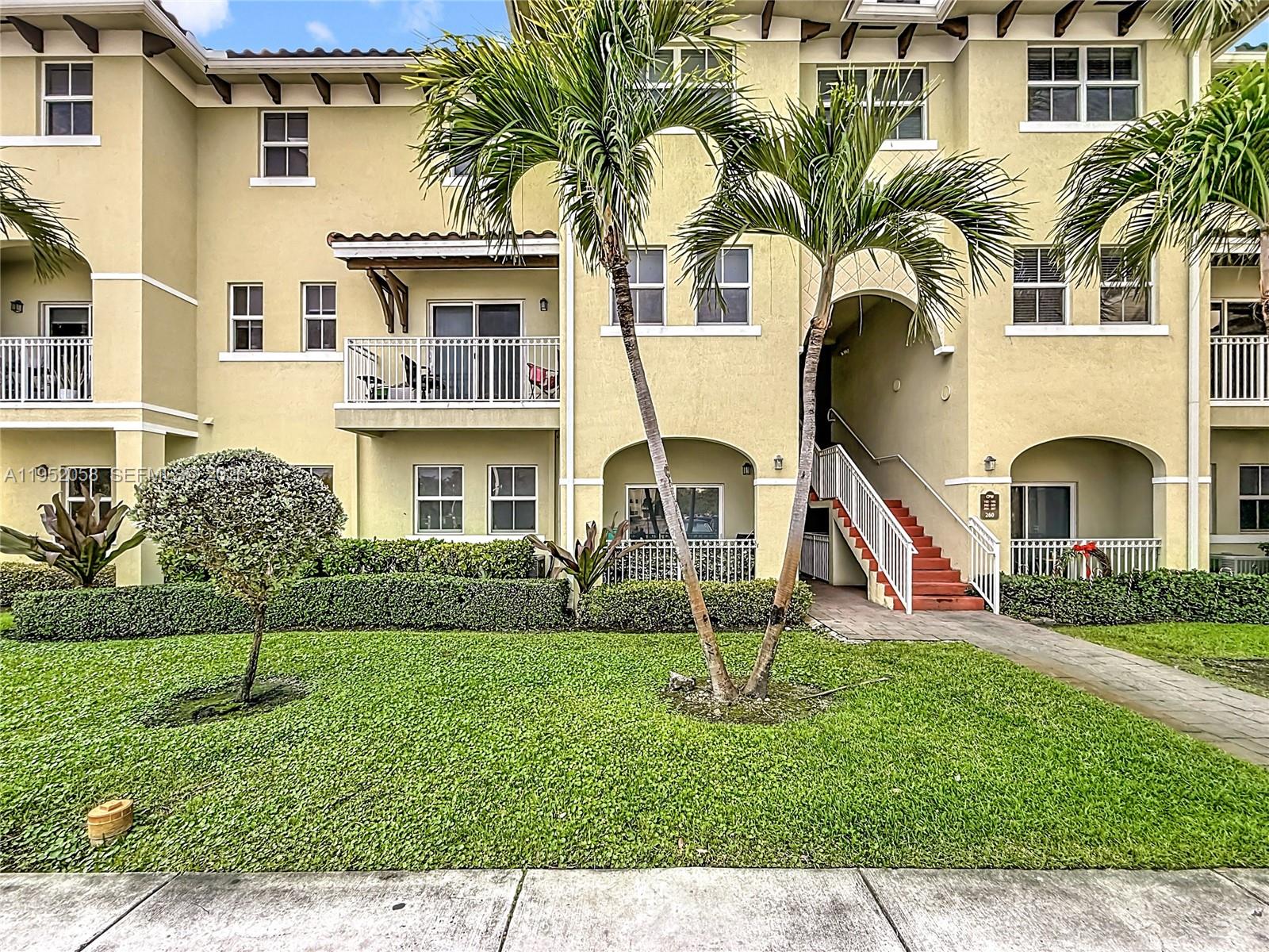 A multi-story apartment building features a tan stucco exterior, palm trees, and a front staircase — 260 NW 109th Ave # 206, Miami FL 33172, MIAMI, FL