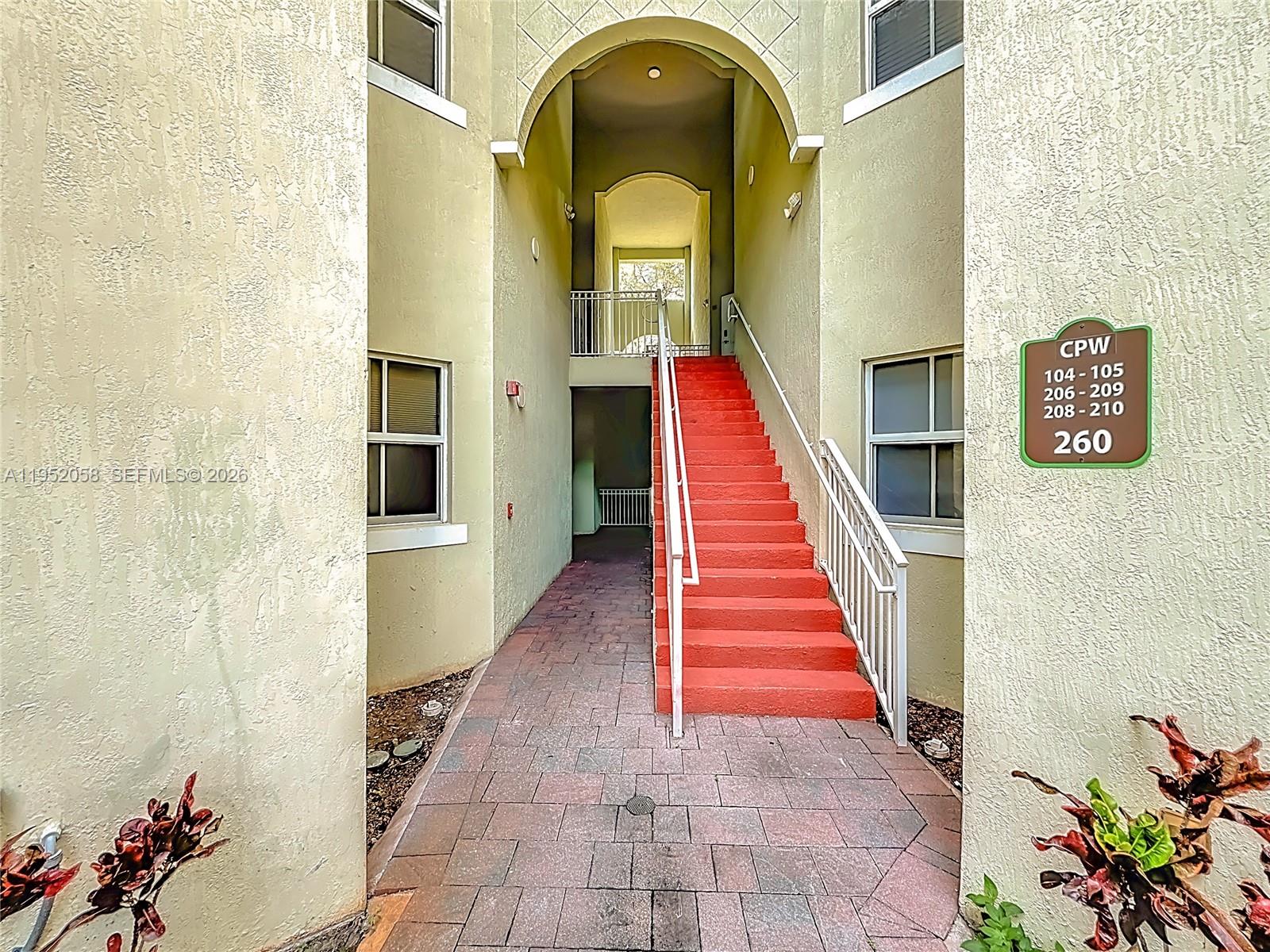 An exterior view shows a set of bright red stairs leading to an apartment entrance — 260 NW 109th Ave # 206, Miami FL 33172, MIAMI, FL
