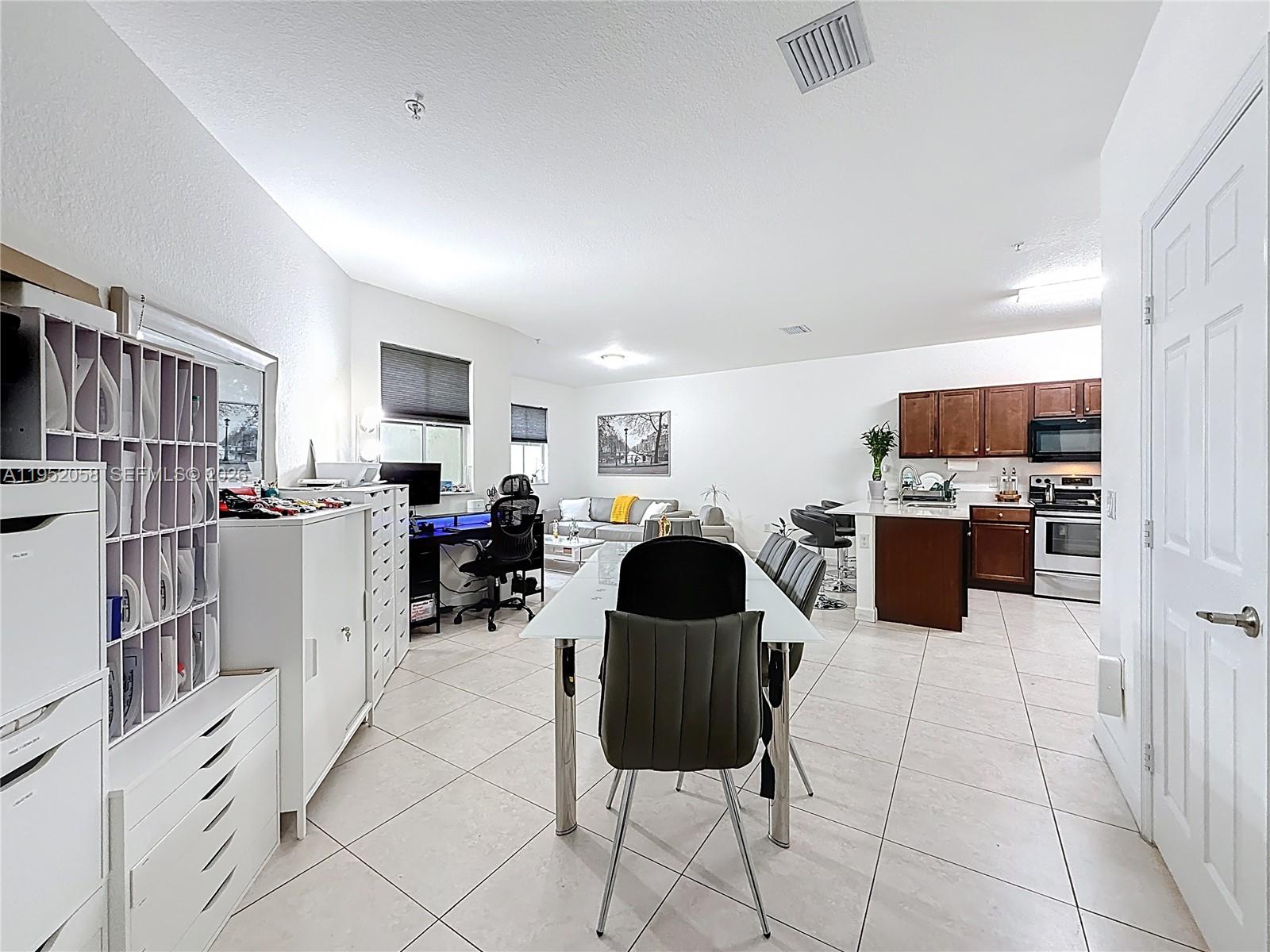 An open-concept living area features a dining table, kitchen with dark cabinets, and office space — 260 NW 109th Ave # 206, Miami FL 33172, MIAMI, FL