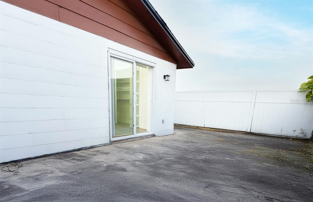 A white concrete block exterior wall features a sliding glass door leading to a patio — 8709 MARLIN COURT, TAMPA, FL