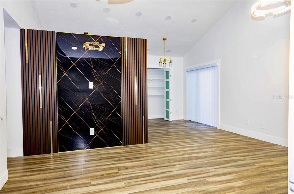 A room features wood-look flooring, a black marble-patterned accent wall with gold trim, and a closet — 8709 MARLIN COURT, TAMPA, FL