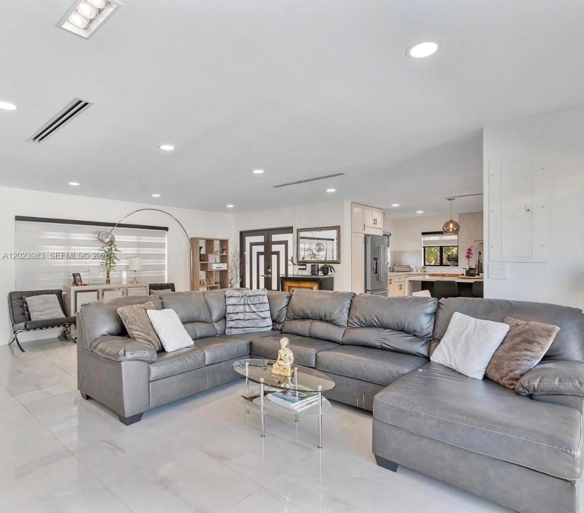 A spacious living room features a large gray sectional sofa, tile flooring, and recessed lighting — HOLLYWOOD, FL