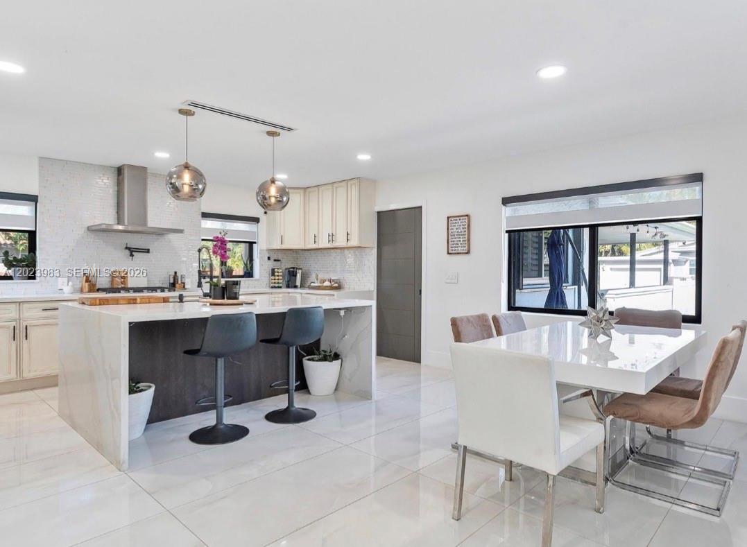 A modern kitchen features a waterfall island, white cabinetry, and an adjacent dining area — HOLLYWOOD, FL