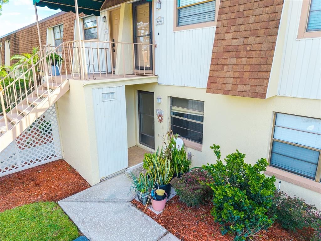 A two-story apartment building exterior features a ground-level entrance, stairs to a balcony, and landscaping — 6085 TOPHER TRAIL UNIT 6085, MULBERRY, FL
