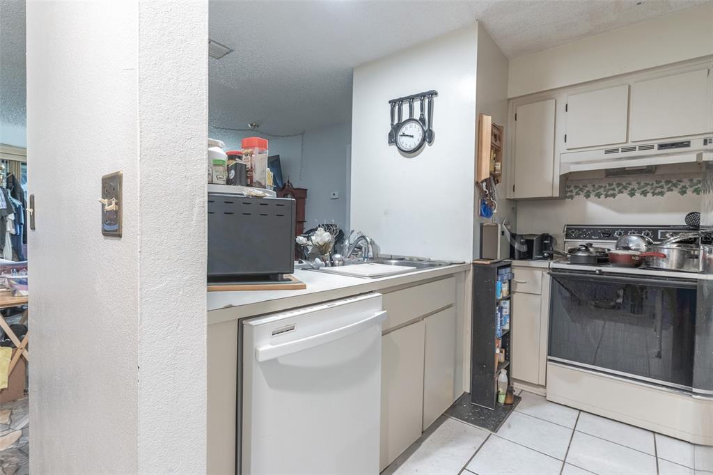 A kitchen features white cabinets, a dishwasher, a stove, and a wall-mounted clock — 6085 TOPHER TRAIL UNIT 6085, MULBERRY, FL