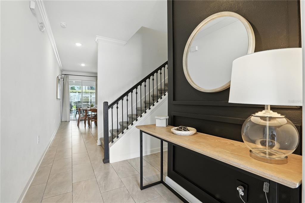 An entryway features a black accent wall with a mirror, console table, and staircase — 1156 KINGSBARN STREET, DAVENPORT, FL