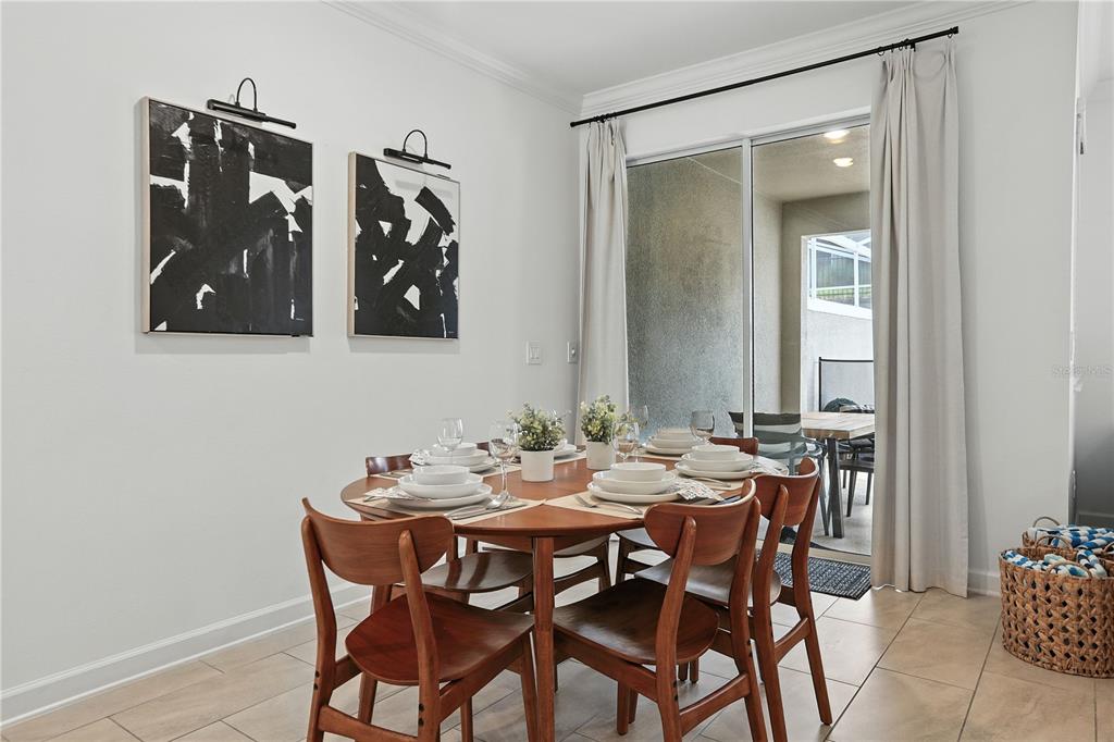 A dining room features a round wooden table, six chairs, and sliding glass doors — 1156 KINGSBARN STREET, DAVENPORT, FL