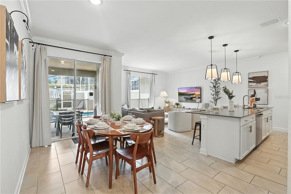 An open-concept kitchen, dining area, and living room feature tile flooring and sliding glass doors — 1156 KINGSBARN STREET, DAVENPORT, FL