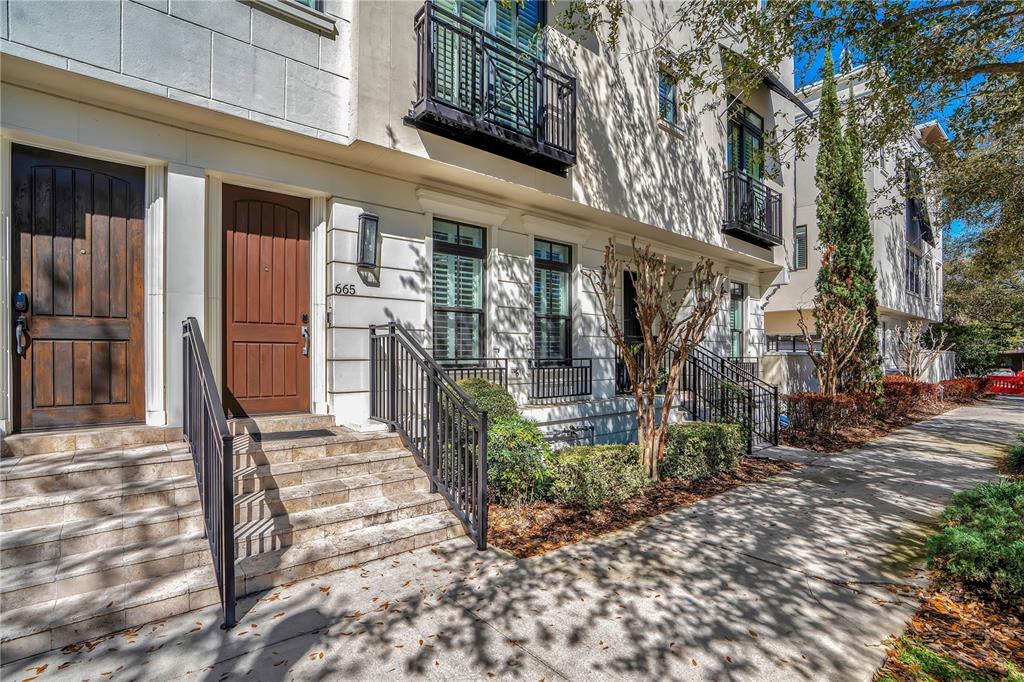 The exterior of a multi-story townhouse features stone steps, dark wood doors, and black railings — 665 JACKSON STREET, ORLANDO, FL