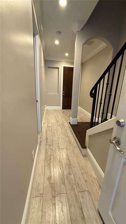 A hallway with light wood-look tile flooring leads to a dark wood door — 665 JACKSON STREET, ORLANDO, FL