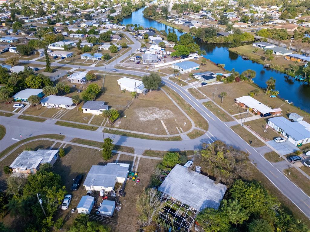 An aerial view shows a residential neighborhood with houses, streets, and a winding canal — 3476 CROTON TERRACE, PORT CHARLOTTE, FL