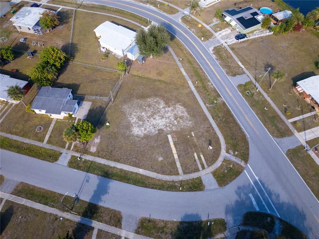 An aerial view shows a vacant corner lot situated between two residential streets — 3476 CROTON TERRACE, PORT CHARLOTTE, FL