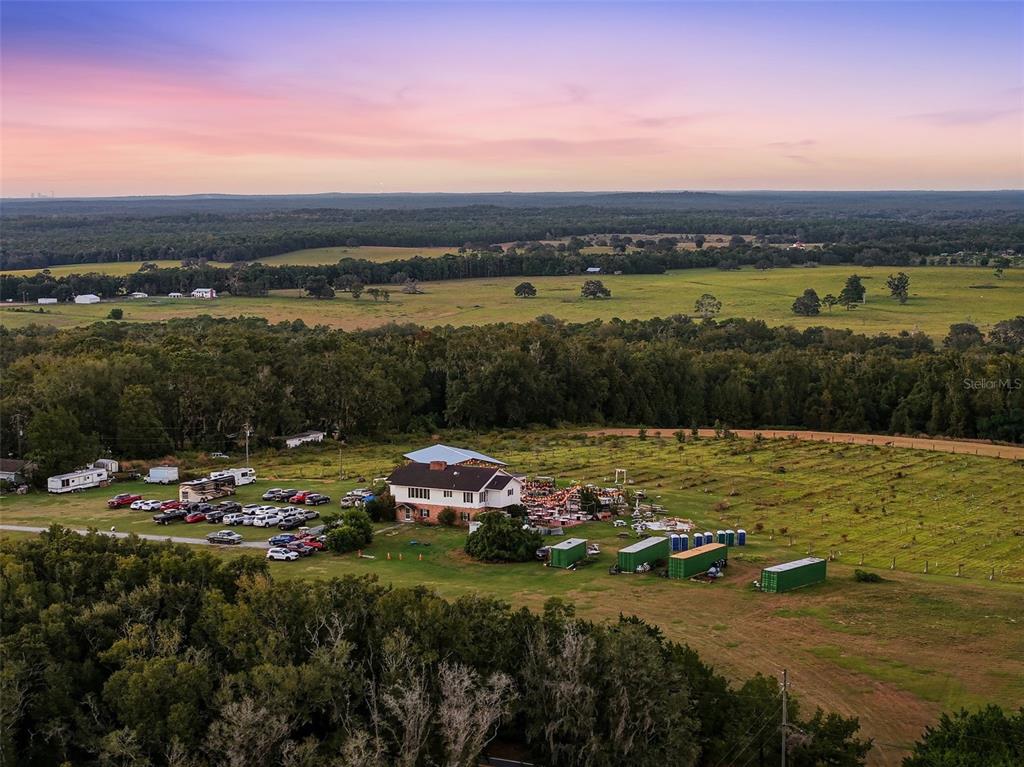 An aerial view shows a house with a large parking area and storage containers nearby — 21509 SNOW HILL ROAD, BROOKSVILLE, FL