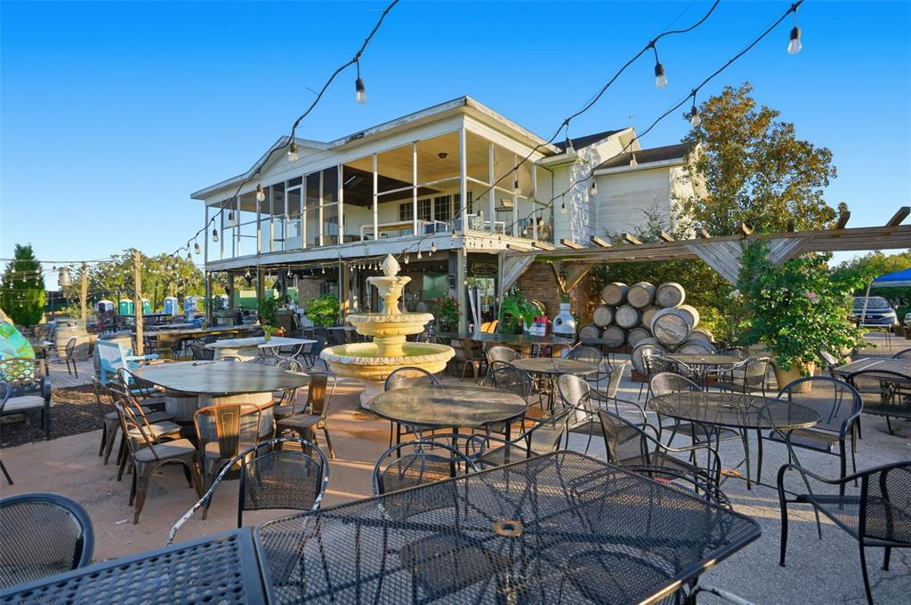 An outdoor patio features metal tables, chairs, a central fountain, and a two-story building — 21509 SNOW HILL ROAD, BROOKSVILLE, FL
