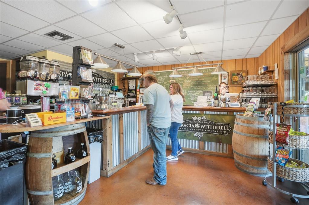 A winery tasting room features a wooden bar, barrel-style displays, and a chalkboard menu — 21509 SNOW HILL ROAD, BROOKSVILLE, FL