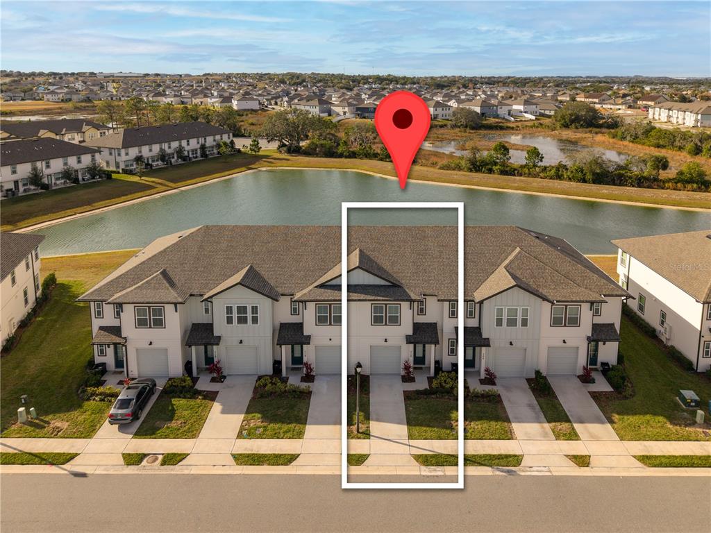 An aerial view shows a row of townhouses with a highlighted unit facing a pond — 710 LONGBOAT DRIVE, DAVENPORT, FL