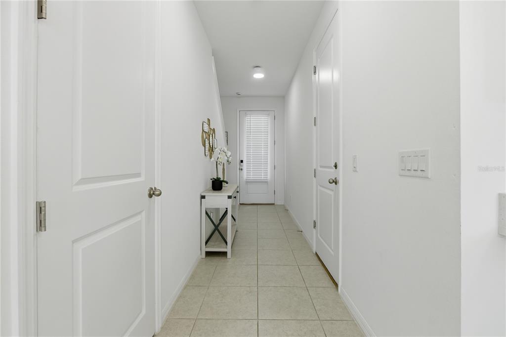 A bright hallway features white walls, tile flooring, a console table, and a front door — 710 LONGBOAT DRIVE, DAVENPORT, FL