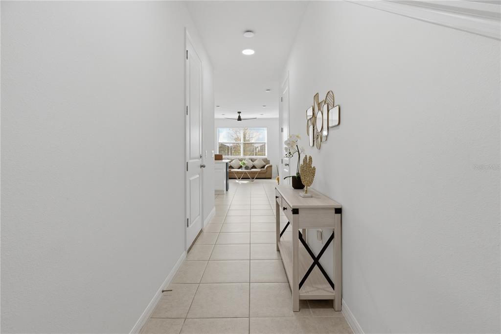 A hallway with tile flooring leads to a living area featuring a console table — 710 LONGBOAT DRIVE, DAVENPORT, FL