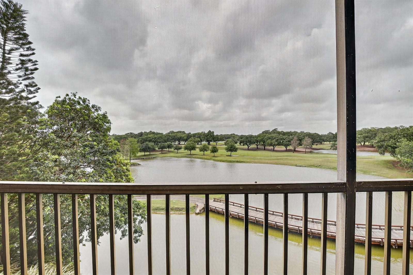 A view from a screened balcony overlooking a pond, a wooden bridge, and a golf course — 3001 W Rolling Hills Circle # 501, Davie FL 33328, DAVIE, FL