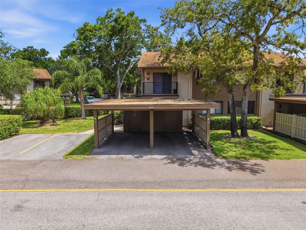 A two-story residential building features a covered carport with storage units in the foreground — 12809 WEDGEWOOD WAY UNIT A, HUDSON, FL