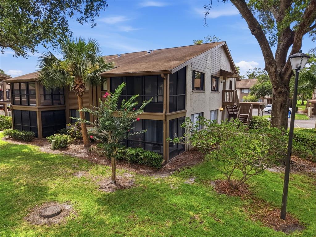 A two-story apartment building with screened-in porches and exterior staircases surrounded by green landscaping — 12809 WEDGEWOOD WAY UNIT A, HUDSON, FL