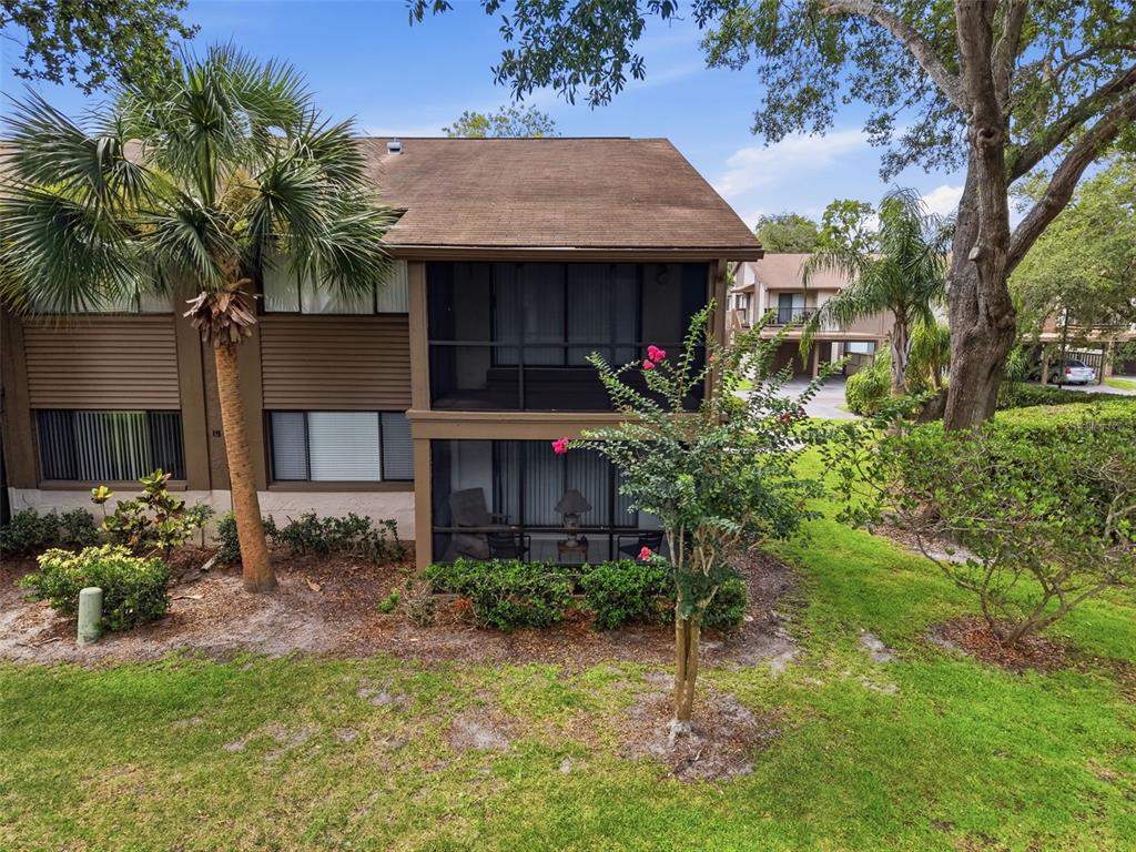 A two-story building with screened-in balconies, a palm tree, and a small flowering tree — 12809 WEDGEWOOD WAY UNIT A, HUDSON, FL