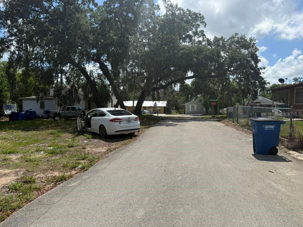 A white sedan is parked on a dirt lot next to a paved residential street — 4818 2ND STREET, SEBRING, FL