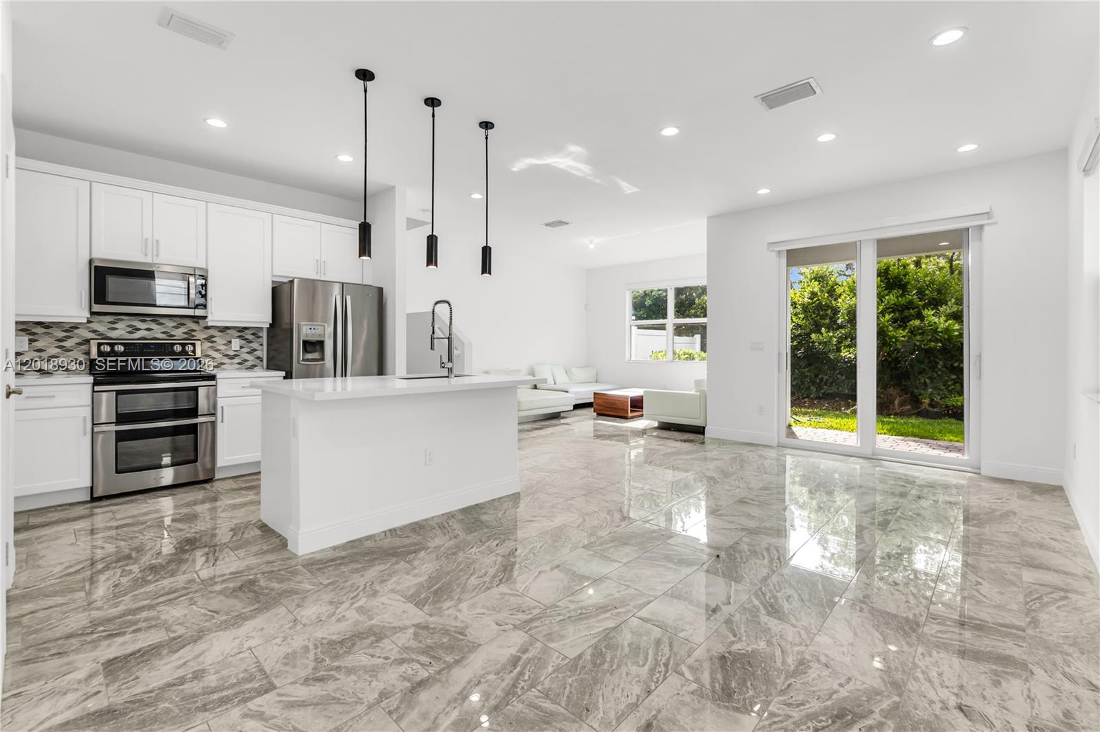 A modern open-concept kitchen and living area features white cabinetry, stainless appliances, and marble flooring — 582 Parsons Way, Deerfield Beach FL 33442, DEERFIELD BEACH, FL