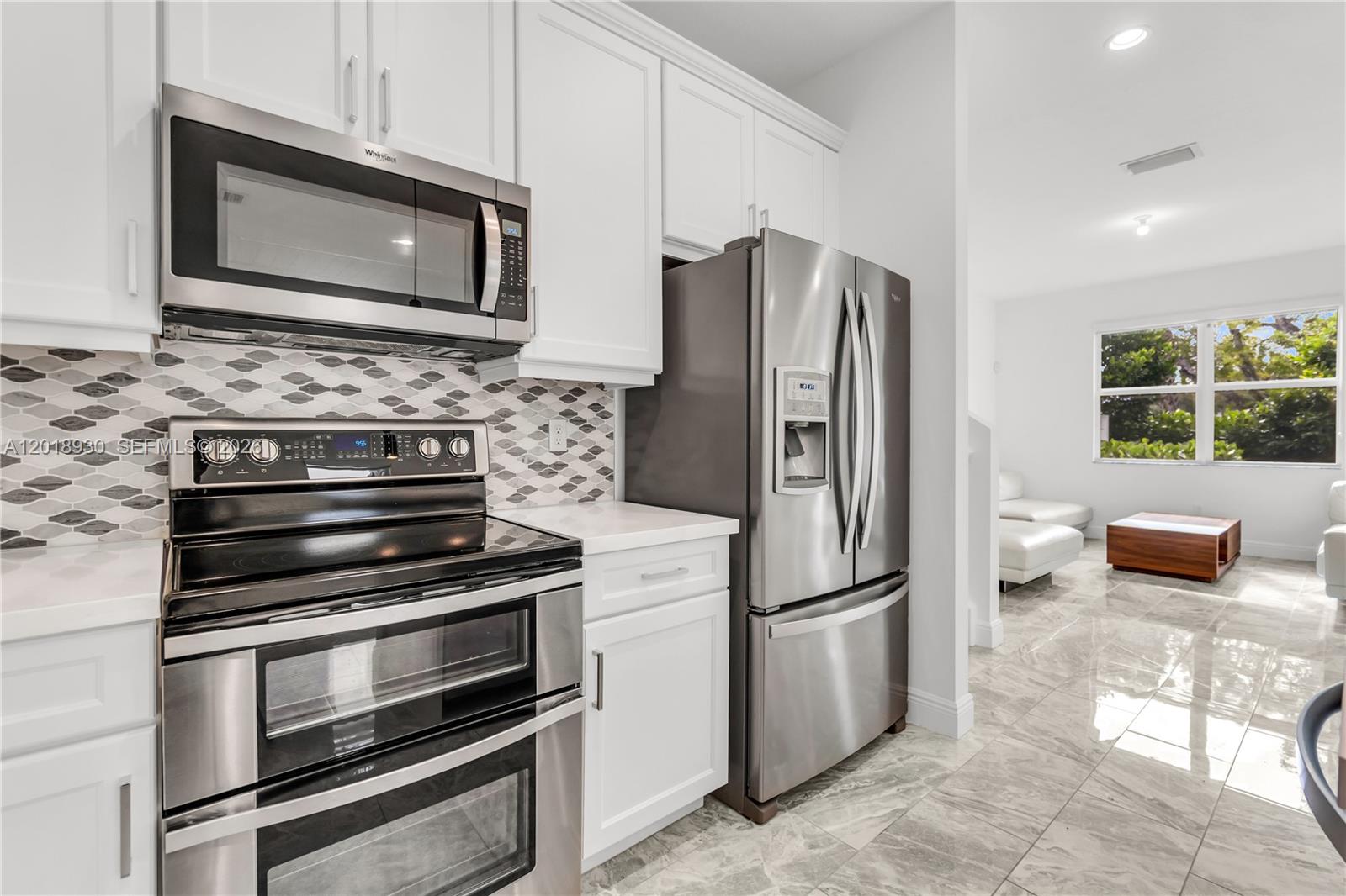 A kitchen features white cabinets, stainless steel appliances, a patterned backsplash, and marble-look tile floors — 582 Parsons Way, Deerfield Beach FL 33442, DEERFIELD BEACH, FL