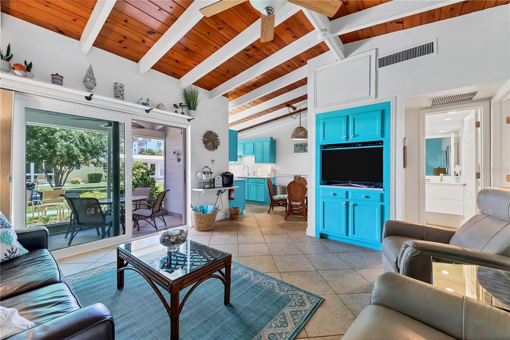 A living room features a vaulted wood-beam ceiling, turquoise cabinetry, and a sliding glass door — 6006 MIDNIGHT PASS ROAD UNIT 16, SARASOTA, FL