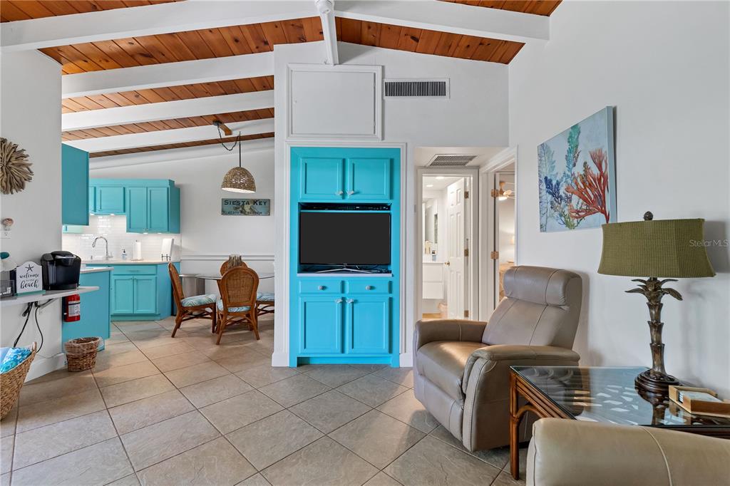 A living room and kitchen area features turquoise cabinetry, tile flooring, and exposed wood beams — 6006 MIDNIGHT PASS ROAD UNIT 16, SARASOTA, FL