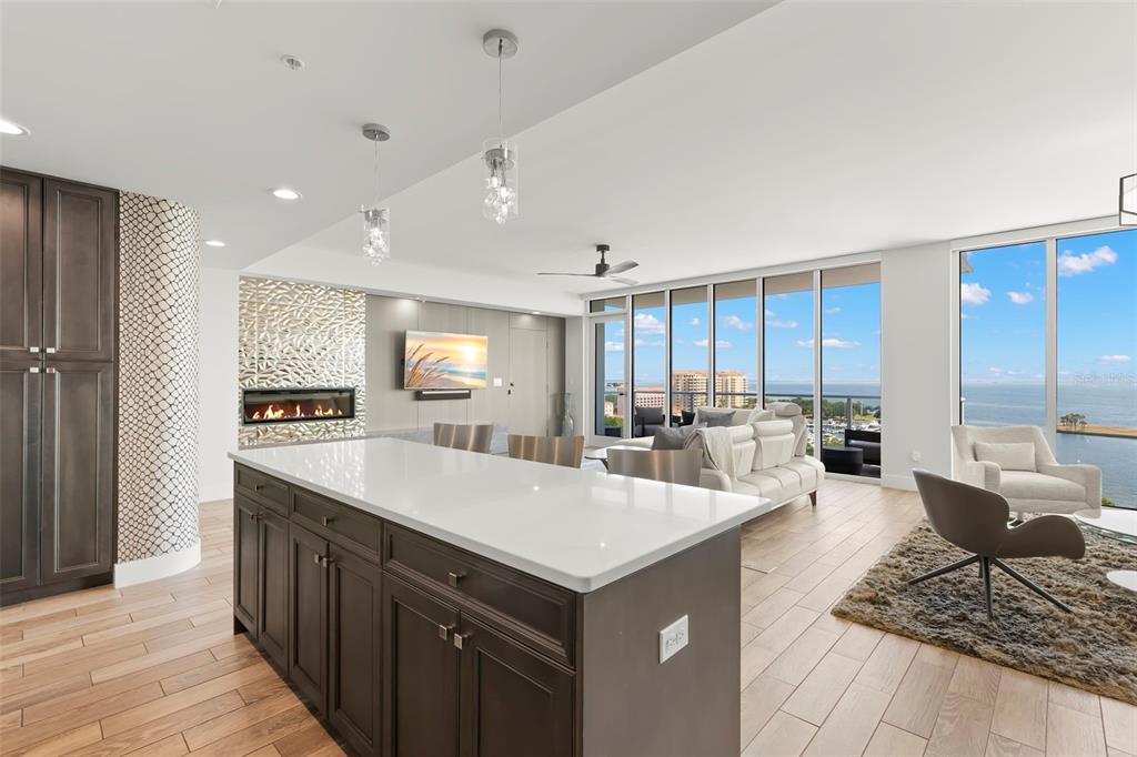 A modern open-concept kitchen and living area with a large island, fireplace, and water views — 176 4TH AVENUE NE UNIT 1102, ST PETERSBURG, FL